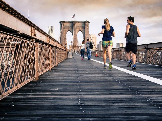 Zwei Leute joggen auf der Brooklyn Bridge.