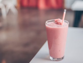 Ein rosa Smoothie mit einem Strohhalm auf einem Tisch.