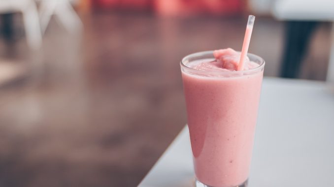 Ein rosa Smoothie mit einem Strohhalm auf einem Tisch.