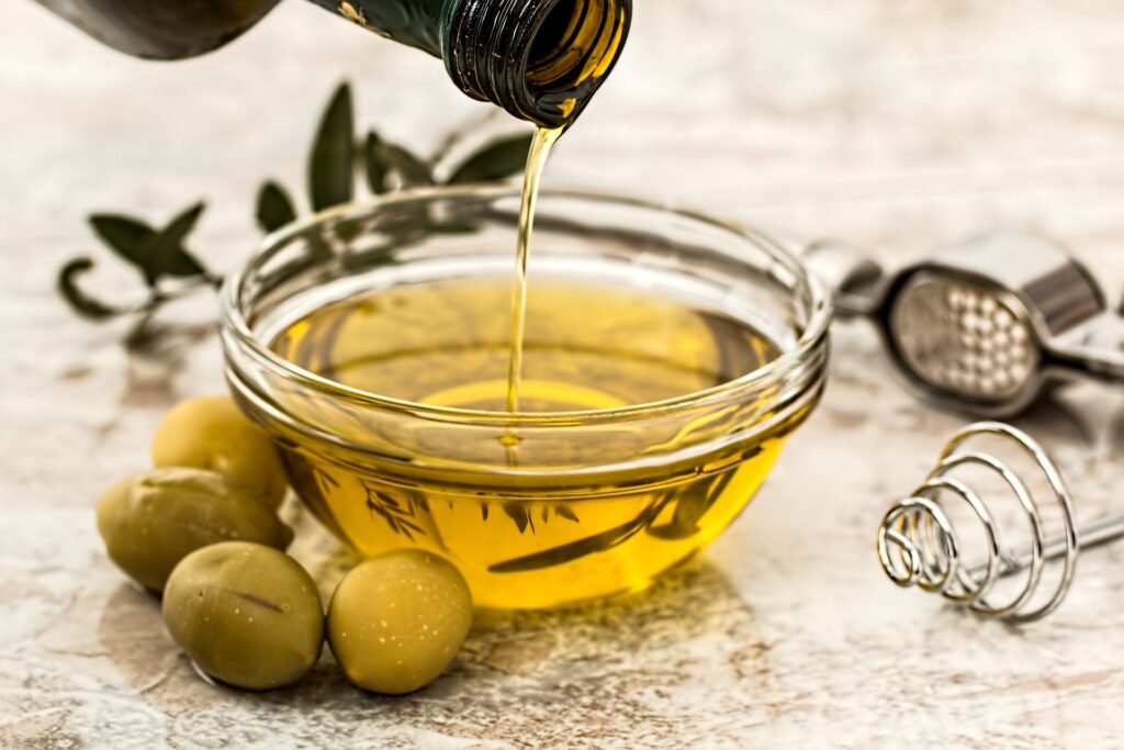Für eine gesunde Mahlzeit wird Olivenöl auf einen Teller mit Oliven gegossen.