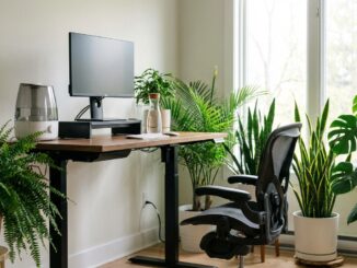 ein modernes heimbüro mit einem desktop computer einem ergonomischen stuhl und mehreren topfpflanzen in der nähe eines fensters mit tageslicht