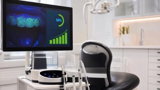 zahnarztpraxis mit einem behandlungsstuhl und einem monitor auf dem eine zahnröntgenaufnahme eine digitale patientenakte und eine grafik zum prozentualen fortschritt angezeigt werden; zahnärztliche instrumente liegen auf einem tablett in der nähe
